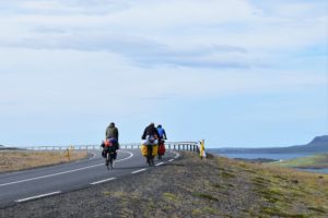 bicyclists cycling along a coastal road with packs