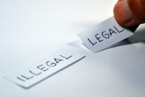 words illegal and lega on paper with fingers choosing legal